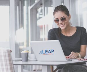 Woman working on laptop and laptop has the LEAP logo.